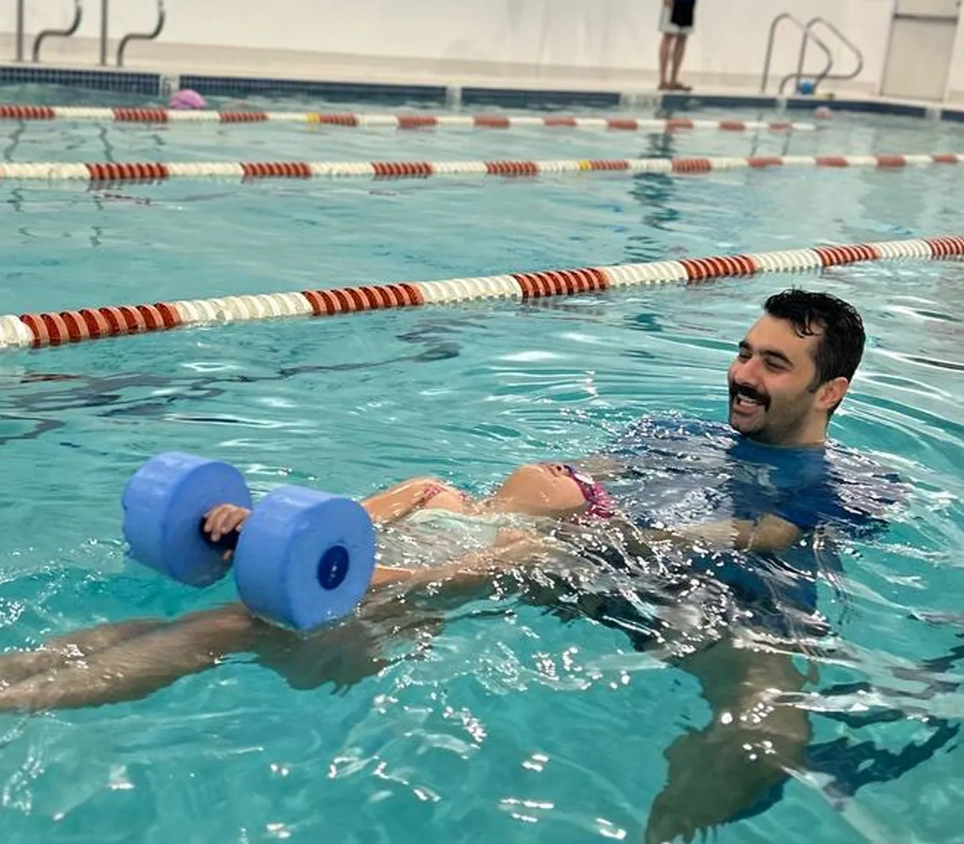 Marina’s Swim School instructor teaching a young swimmer proper body position for efficient swimming in a warm indoor pool.
