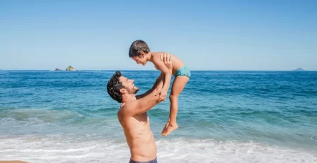 father-lifting-son-beach