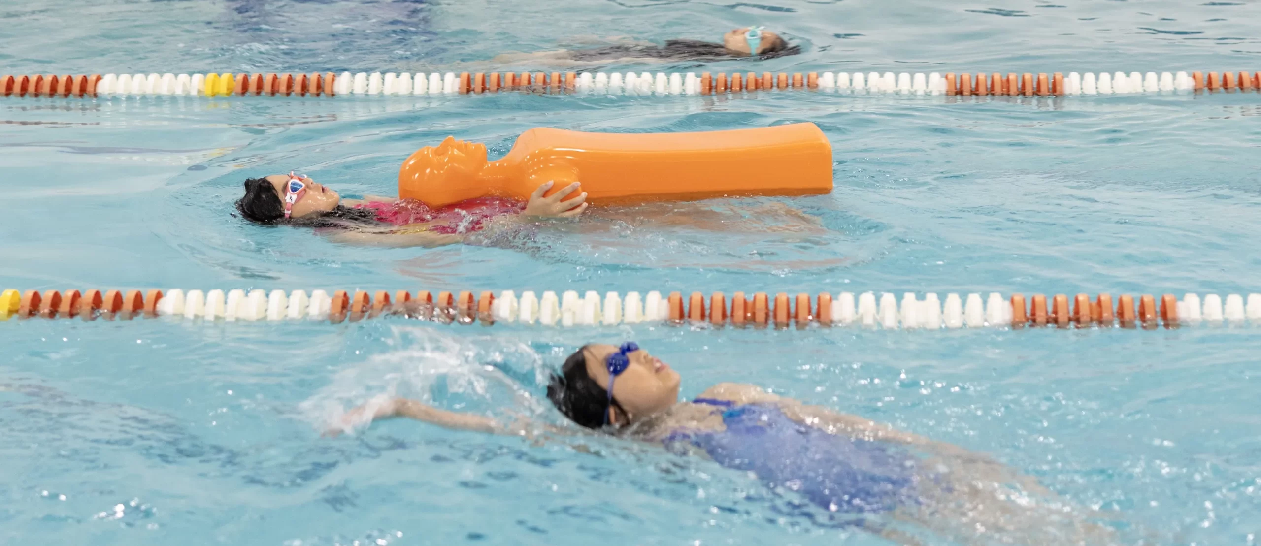 Swimmers practicing lifesaving and rescue techniques with a manikin during Marina’s Swim School Patrol Program, affiliated with the Lifesaving Society at Marina swim school.